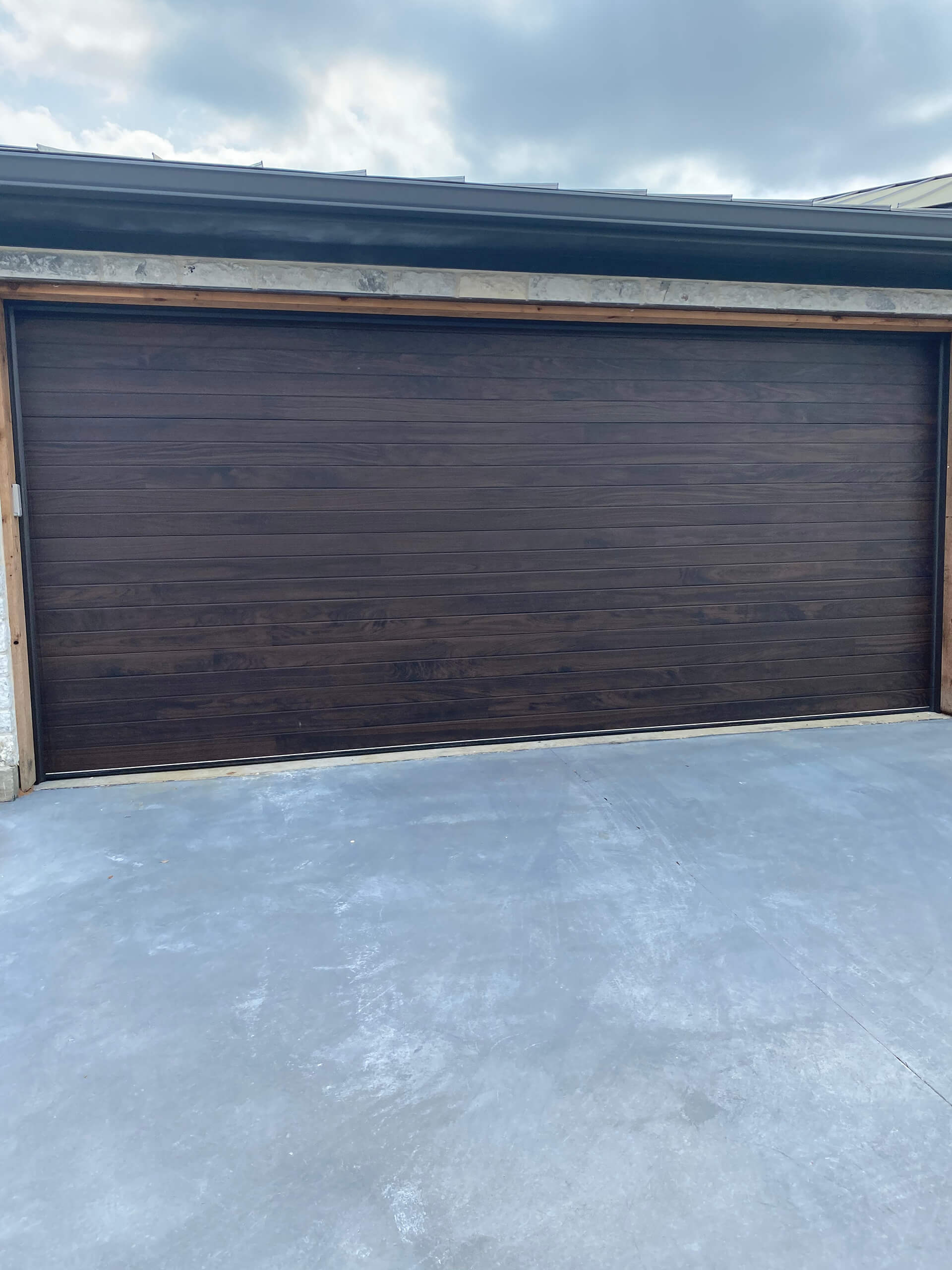 Dark wood-tone garage door repaired and serviced by Door Pro Plus on a home in Marble Falls, TX