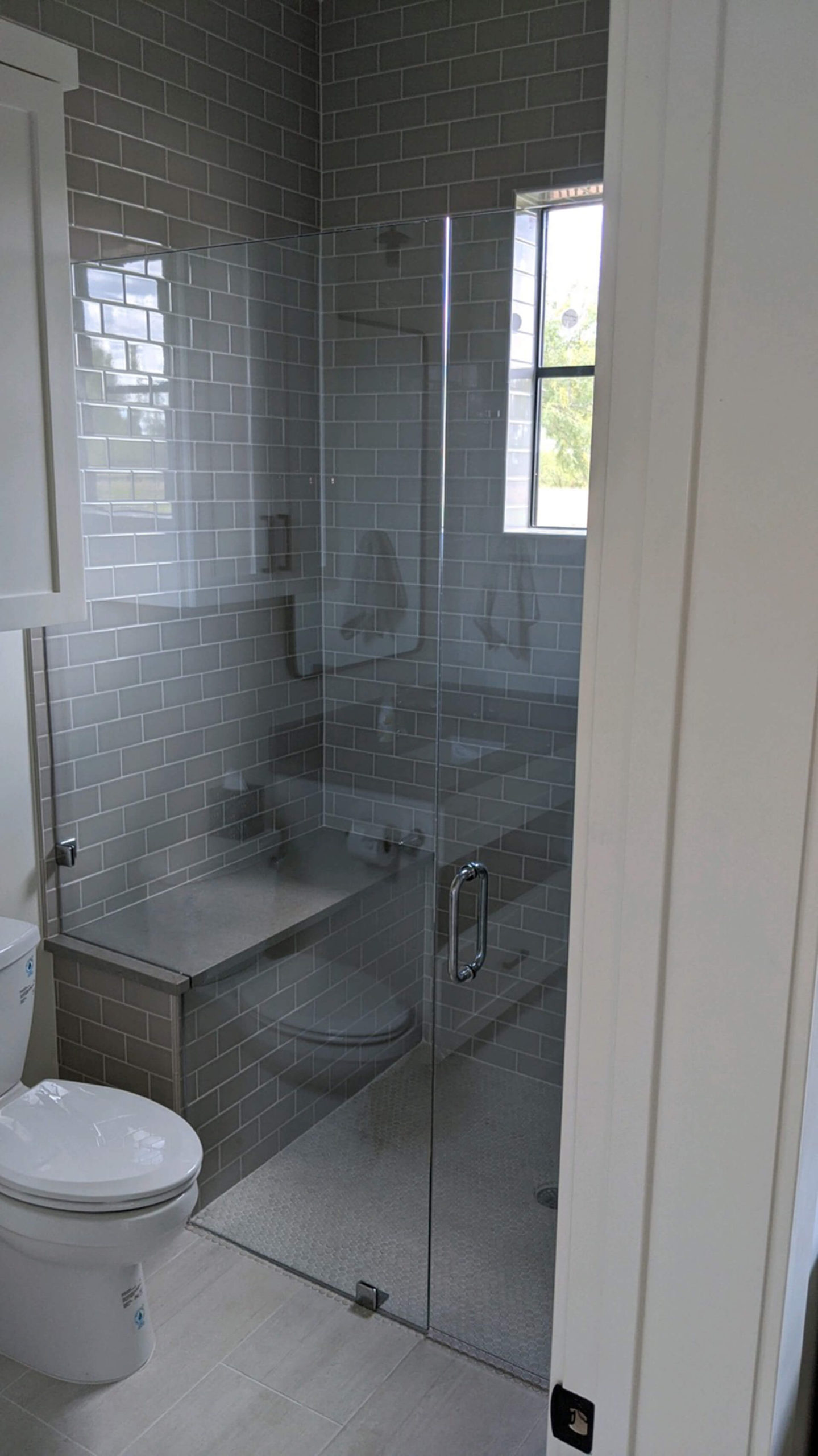 Frameless glass shower enclosure with chrome hardware and a corner bench, installed by Door Pro Plus in Marble Falls, TX