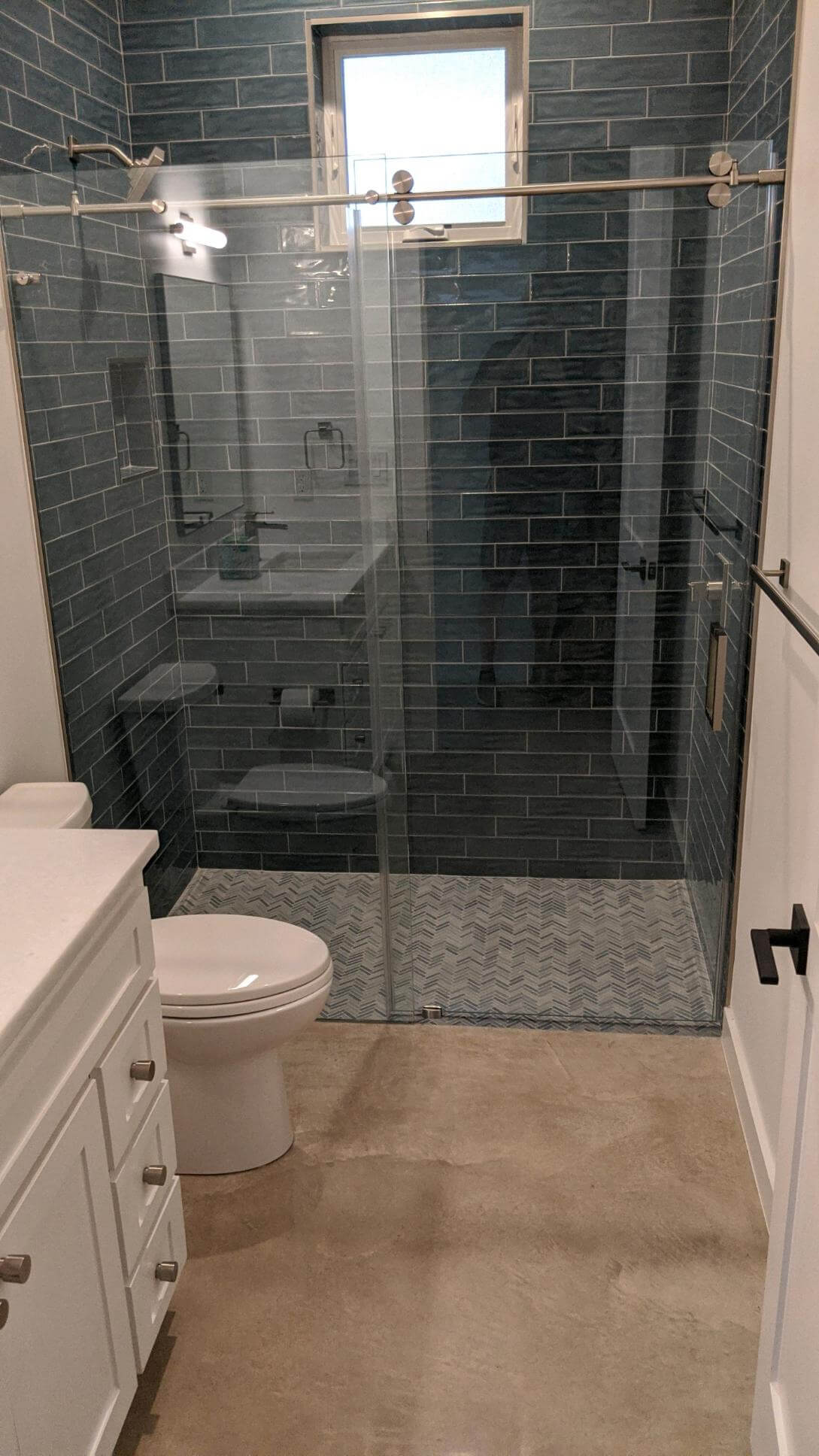 Frameless sliding glass shower door over blue subway tile, installed by Door Pro Plus for a Hill Country home